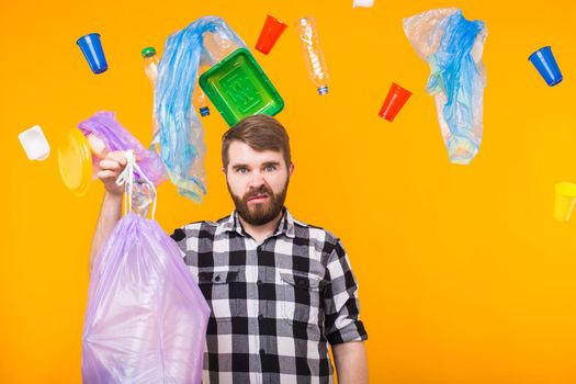 Plastic recycling problem, ecology and environmental disaster concept - Angry man holding garbage bag on yellow background.