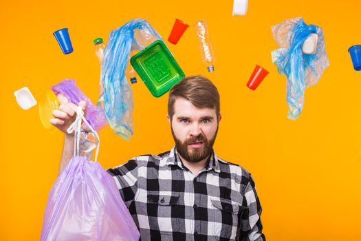 World Environment Day, plastic recycling problem and environmental disaster concept - Angry man holding garbage bag for recycling and showing thumb down on yellow background.