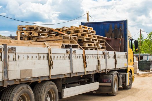 Truck at the construction site transporting wooden pallets, industrial freight or timber cargo.