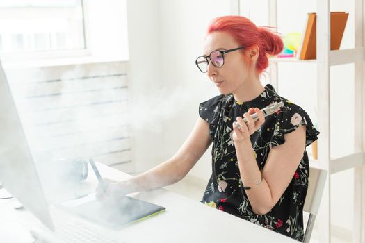 Creative, graphic designer, people concept - young creative woman smoking a vape while working in a graphic tablet.