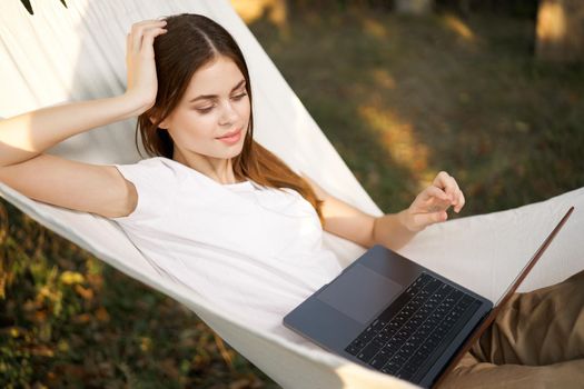 woman lies in a hammock with laptop on nature vacation travel. High quality photo