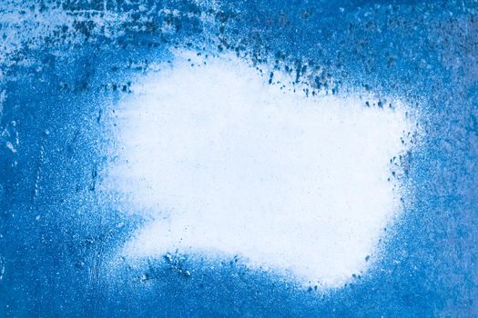 White stain of paint on the wall surface of an old blue metal texture background. Copy space for text and design.
