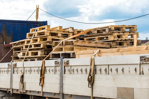 Truck at the construction site transporting wooden pallets, industrial freight or timber cargo.