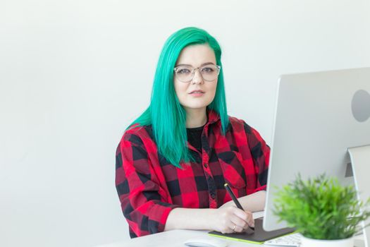 Graphic designer, animator and illustrator concept - young woman with green hair working at the laptop.