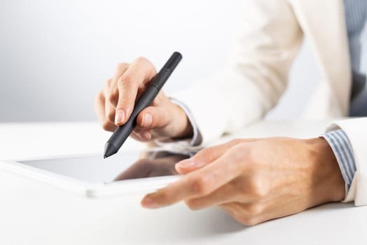 Man in business suit using tablet computer. Close-up of male hands holding pen and tablet gadget. Businessman at workplace in office. Business occupation and mobility, internet smart technology in job