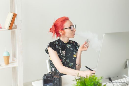 Creative, graphic designer, people concept - young creative woman smoking a vape while working in a graphic tablet.