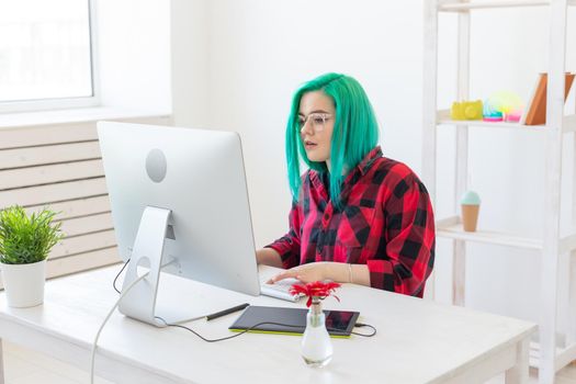 Illustrator, graphic designer, animator and artist concept - creator woman with beautiful green hair and glasses drawing in laptop.