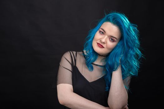 Style and fashion concept - Young and attractive woman with blue hair posing over black background.