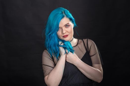 Style and fashion concept - Young and attractive woman with blue hair posing over black background.