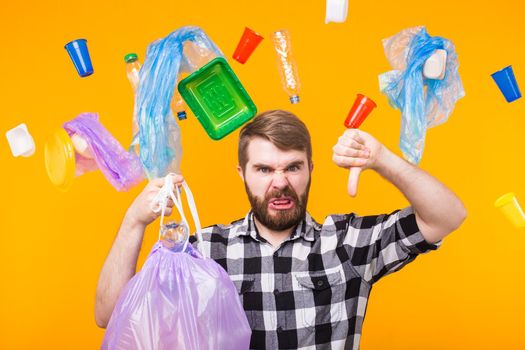 World Environment Day, plastic recycling problem and environmental disaster concept - Angry man holding garbage bag for recycling and showing thumb down on yellow background.