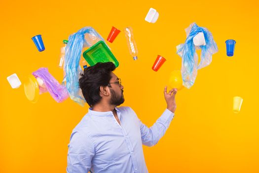 Environmental pollution, plastic recycling problem and waste disposal concept - surprised indian man holding garbage bag on yellow background