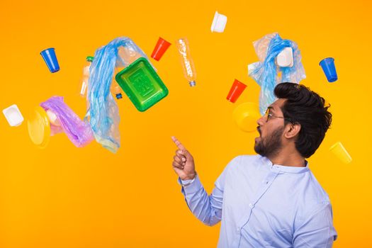 Plastic recycling problem, ecology and environmental disaster concept - Surprised Indian man point on trash on yellow background.