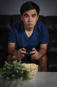 young man playing video game with joystick in the living room at night