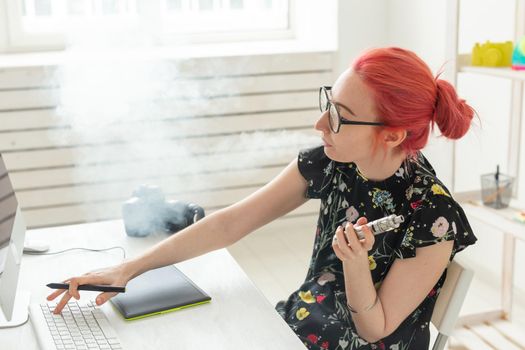 Creative, graphic designer, people concept - young creative woman smoking a vape while working in a graphic tablet.