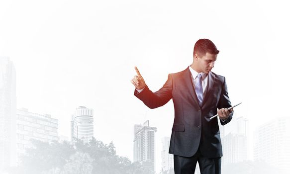 Businessman looking into documents and pointing away on white background. Front view of standing man in business suit and tie. Successful business person in formal wear gesturing with raised hand