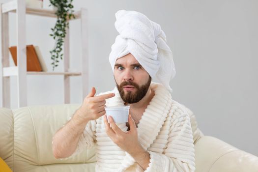 Portrait of man applying effective cream on his facial skin. Spa at home, body and skin care for male concept