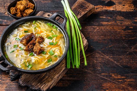 Chicken soup with noodles and vegetables. Dark wooden background. Top view. Copy space.