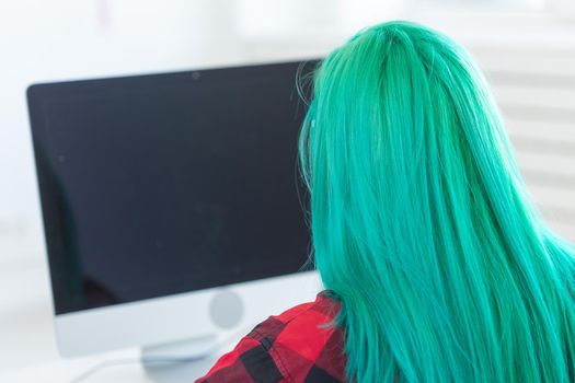 Work, business, style, people concept - perspective from behind of woman with green hair working at the laptop.