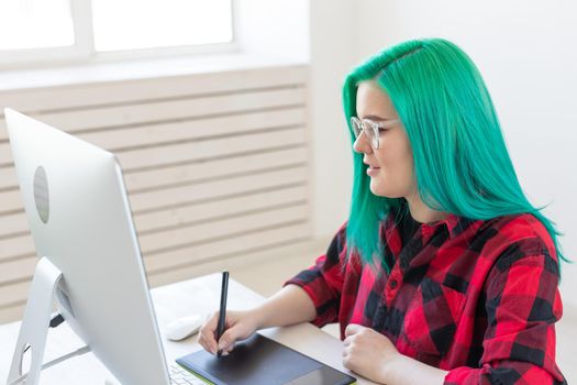 Illustrator, graphic designer, animator and artist concept - creator woman with beautiful green hair and glasses drawing in laptop.