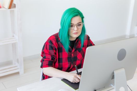 Designer, illustrator, artist and people concept - portrait of contemporary young woman with green hair using laptop and graphic tablet while working.