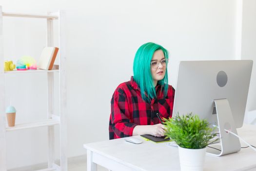 Illustrator, graphic designer, animator and artist concept - creator woman with beautiful green hair and glasses drawing in laptop.