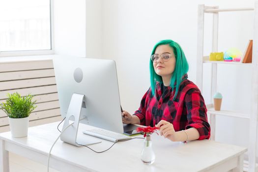 Designer, illustrator, artist and people concept - portrait of contemporary young woman with green hair using laptop and graphic tablet while working.
