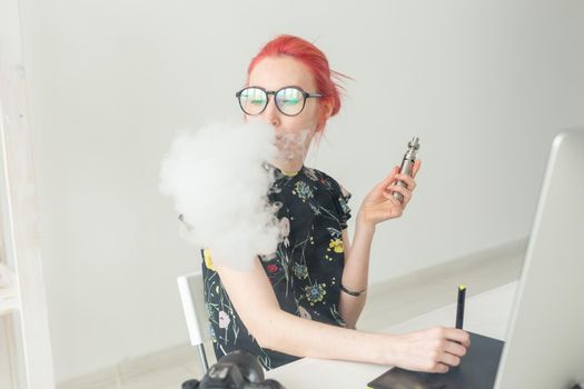 graphic designer concept - Female graphic designer working on computer while using graphic tablet at desk in the office and smoking a vape.