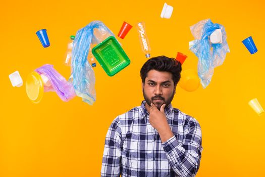 Problem of trash, plastic recycling, pollution and environmental concept - Serious Indian man looking forward on yellow background. He is thinking about ecology.