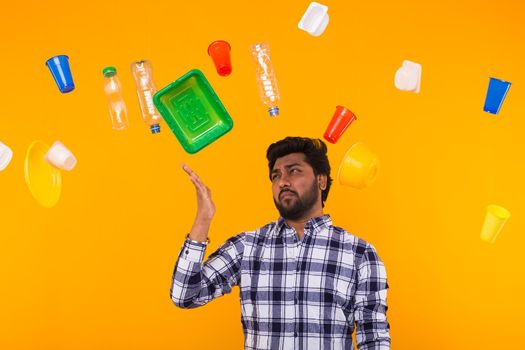 World Environment Day, plastic recycling problem and environmental disaster concept - Sad Indian man looking on trash on yellow background.