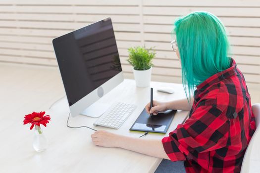 Graphic designer, people concept - Young designer female hipster with graphic tablet working in office.