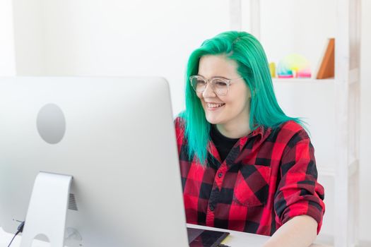Illustrator, graphic designer, animator and artist concept - creator woman with beautiful green hair and glasses drawing in laptop.