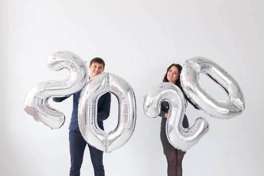 New year, celebration and holidays concept - love couple with sign 2020 made of silver balloons for new year on white background.