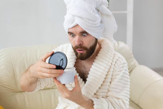 Portrait of man applying effective cream on his facial skin. Spa at home, body and skin care for male concept