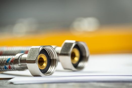Flexible steel water hoses laying on table. Close up water fittings and connections with segments of braided hose. Plumbing supply shop advertising. house hydraulic infrastructure installation.