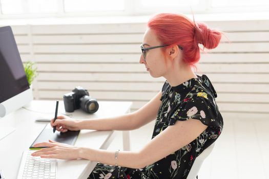 Illustrator, graphic designer, animator and artist concept - creator woman with beautiful red hair and glasses drawing in laptop.