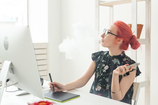 graphic designer concept - Female graphic designer working on computer while using graphic tablet at desk in the office and smoking a vape.