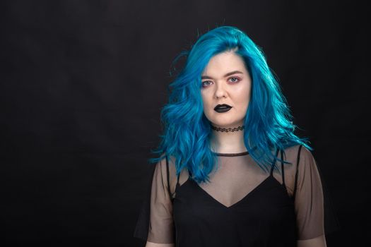 people, fashion and hair concept - close-up portrait of young woman in black dress with blue hair on black .