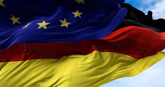 The national flag of Germany waving in the wind together with the European Union flag blurred in the foreground. Politics and finance. Germany is a member state of the European Union