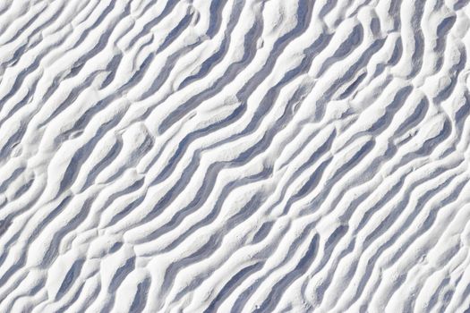 White texture of Pamukkale calcium travertine in Turkey, pattern of diagonal waves, close-up.