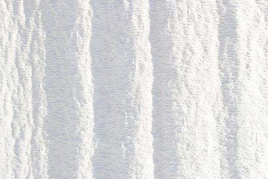 Background, white texture of Pamukkale calcium travertine in Turkey, vertical stripes, top view.