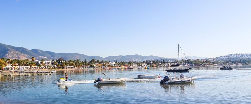 Beautiful bay with calm water, sandy beach, boats and yachts. Small town and green mountains on the coast of the Aegean sea