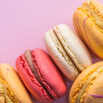 Colorful french cookies macarons set on pink background. Tasty fruit, almond sweet cookies, cake macaron. Holiday backdrop design.