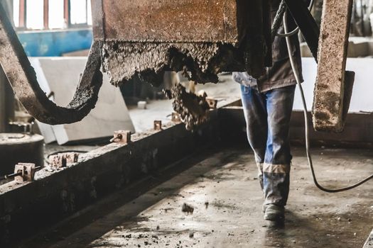 Industrial worker controls the flow of concrete gravel mix from a mixer to the reinforcement workshop, selective focus.