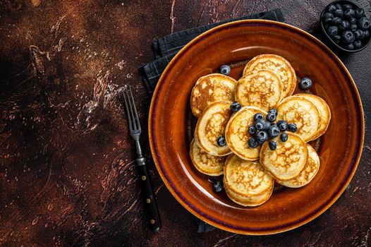 Plate with pancakes with fresh blueberries and syrup . Dark background. Top View. Copy space.