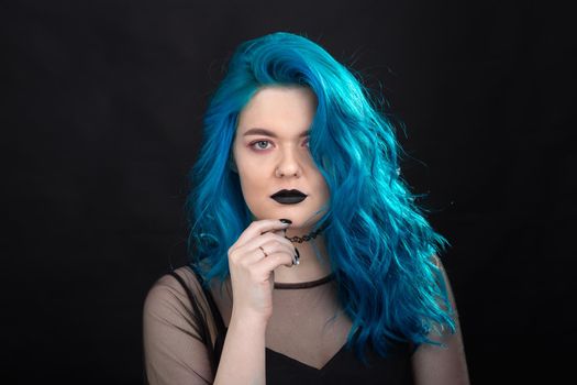 People and fashion concept - Close up portrait of woman with blue long hair over black background.