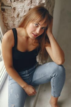 Beautiful girl in a studio. Stylish girl near gray wall. Lady in a black t-shirt