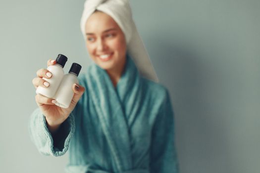 Girl in a studio. Lady with cream. Woman in a blue bathrobe