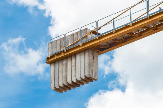 A counterweight of concrete blocks on the tail of a tower crane industrial equipment against a blue sky. Close-up.