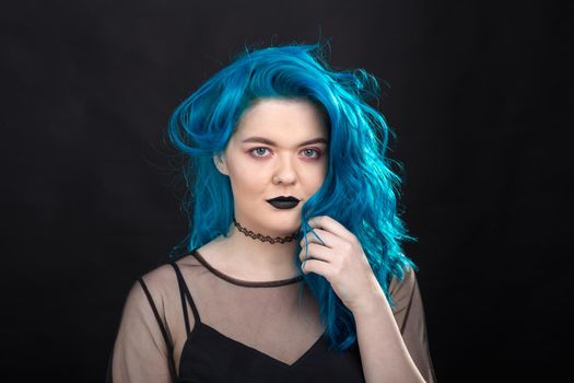 Style and fashion concept - Young and attractive woman with blue hair posing over black background.