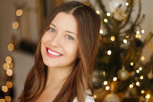 Christmas time and holiday mood concept. Happy smiling woman and decorated xmas tree lights on background.